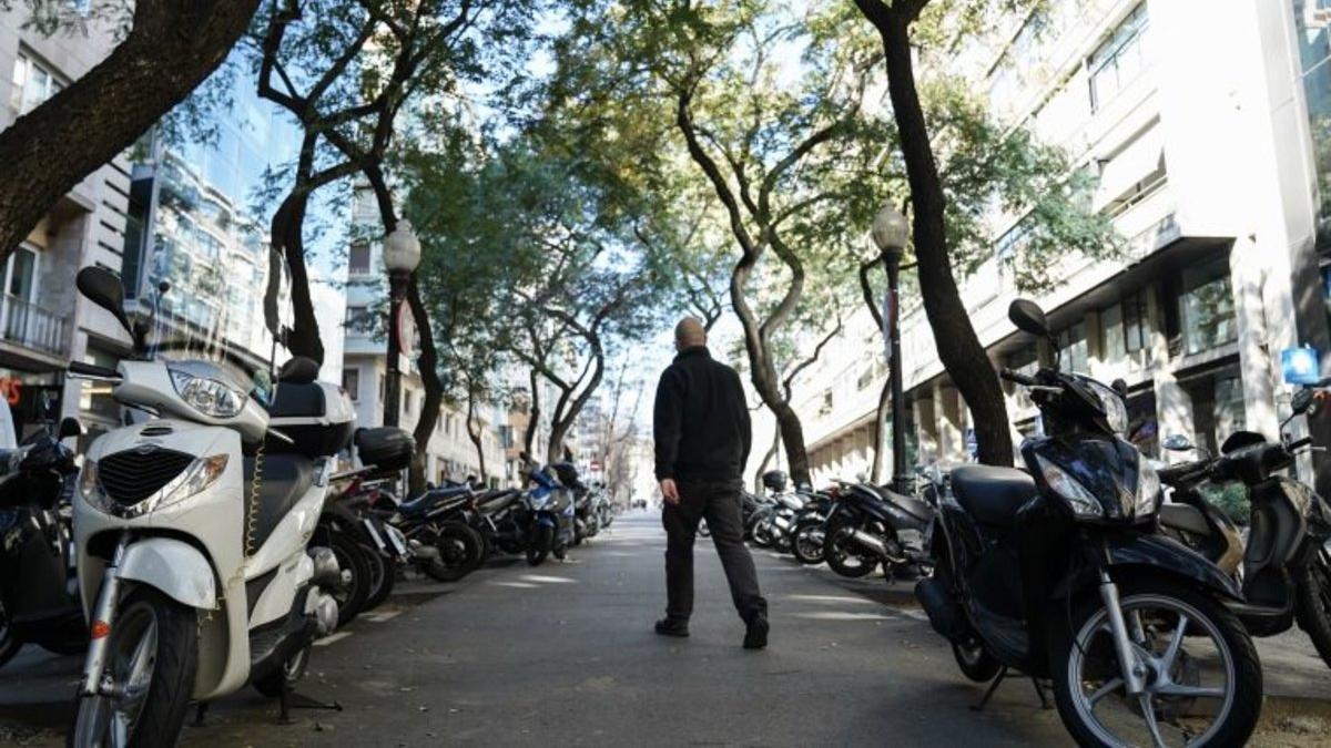 Un hombre caminando en medio de un párking de motos, en Barcelona.