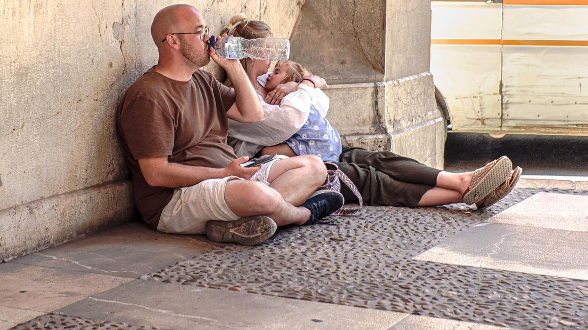 Unos turistas se refugian en la sombra por las altas temperaturas en Palma