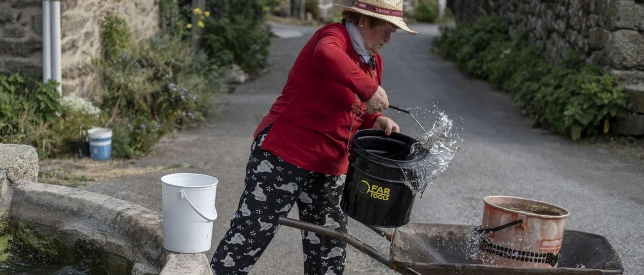 Una vecina recoge cubos de agua en la franja limitada de suministro.