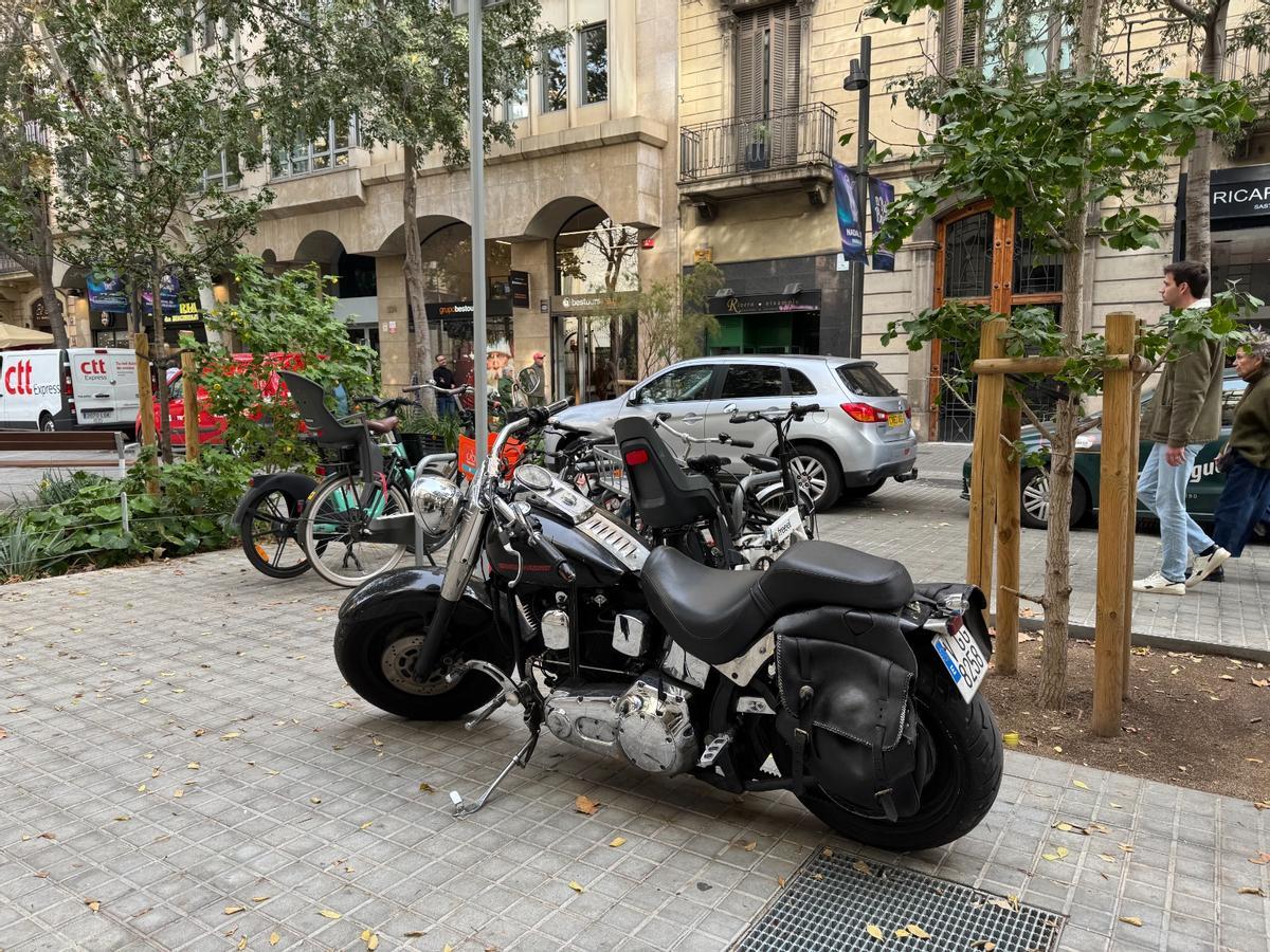 Una moto trata de pasar desapercibida en Consell de Cent, junto al aparcamiento de bicicletas.