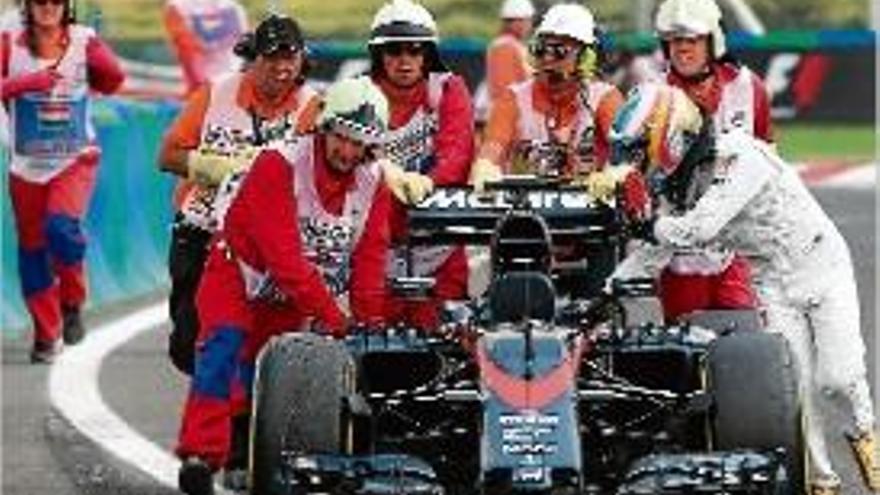 Fernando Alonso empeny el seu McLaren camí del box.