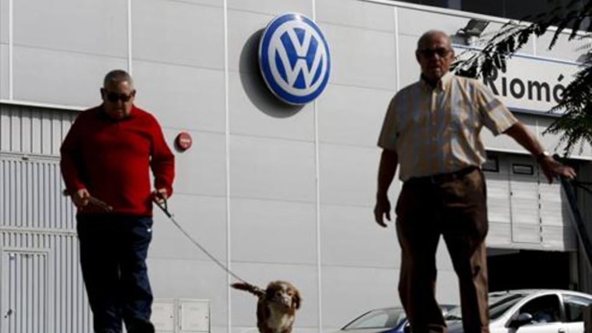 Unos hombres pasean frente a un concesionario de Volkswagen en Sevilla, ayer.