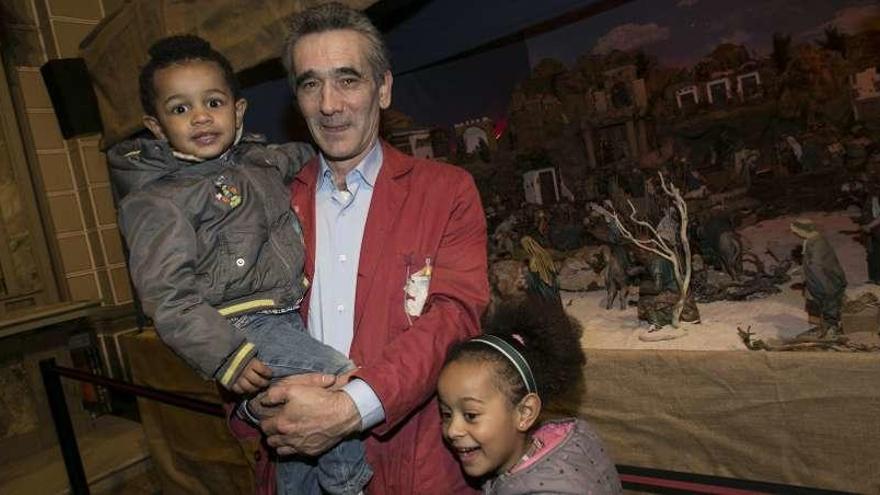 Jorge Piñeiro y sus nietos Shakira y Abraha, ante el belén mecanizado de la iglesia de San Juan.