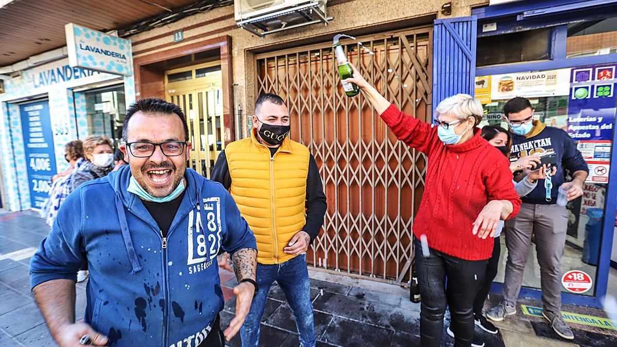 Uno de los afortunados, Carlos, muestra su alegría en la administración de Callosa que repartió el premio, donde otra premiada, Estefanía, brinda junto a las loteras.