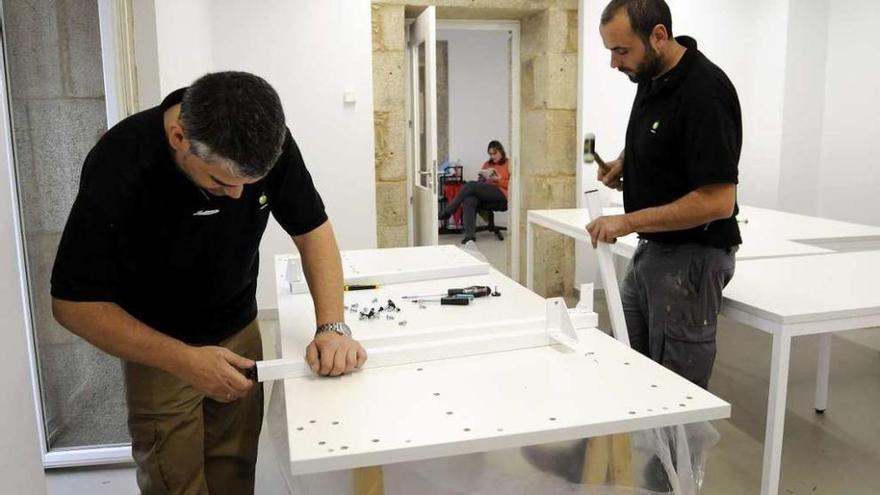 Dos trabajadores colocan mesas en una de las salas de la biblioteca. // Bernabé/Javier Lalín