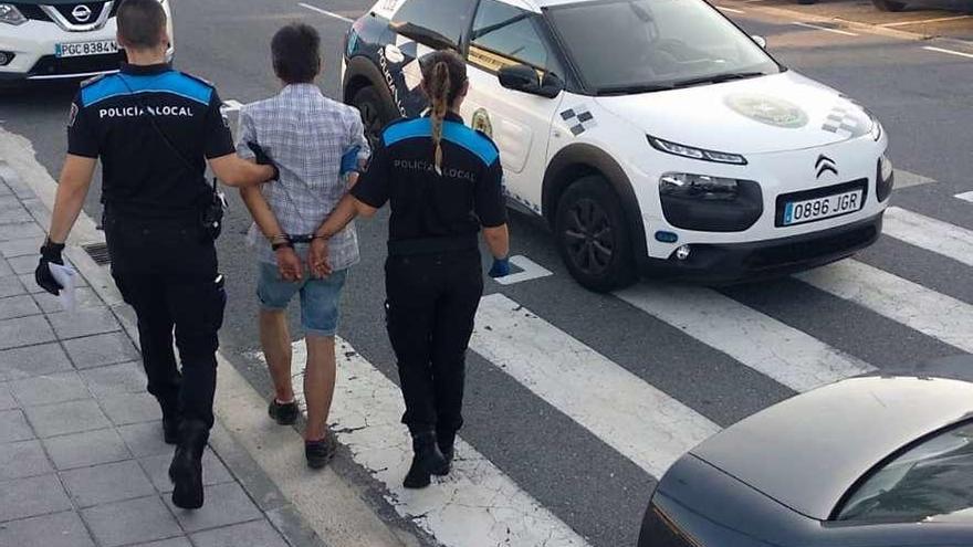 Los agentes de la Policía Local llevándose detenido al presunto autor. // FdV