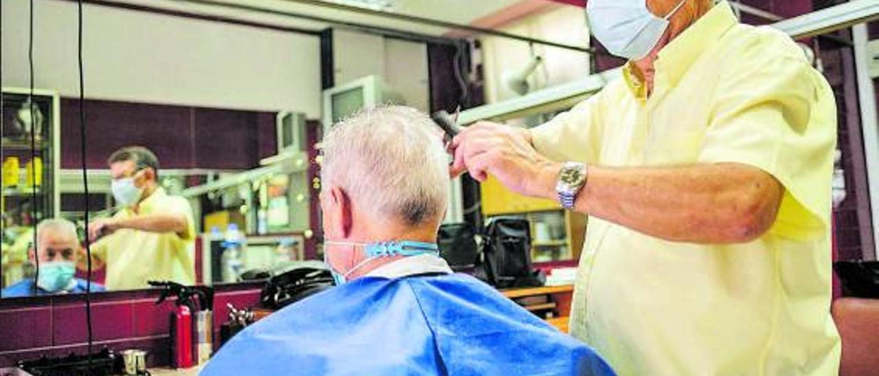 Un peluquero con un cliente en su peluquería.