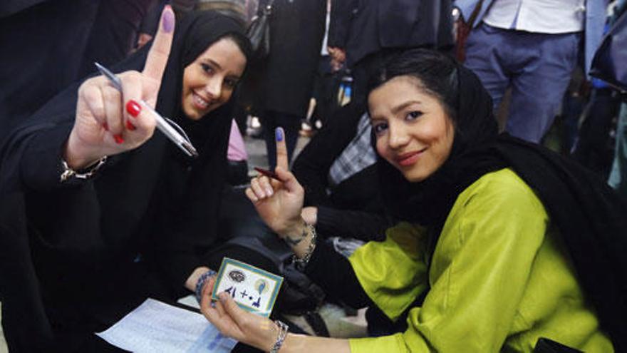 Dos jóvenes iraníes, sonrientes antes de votar.