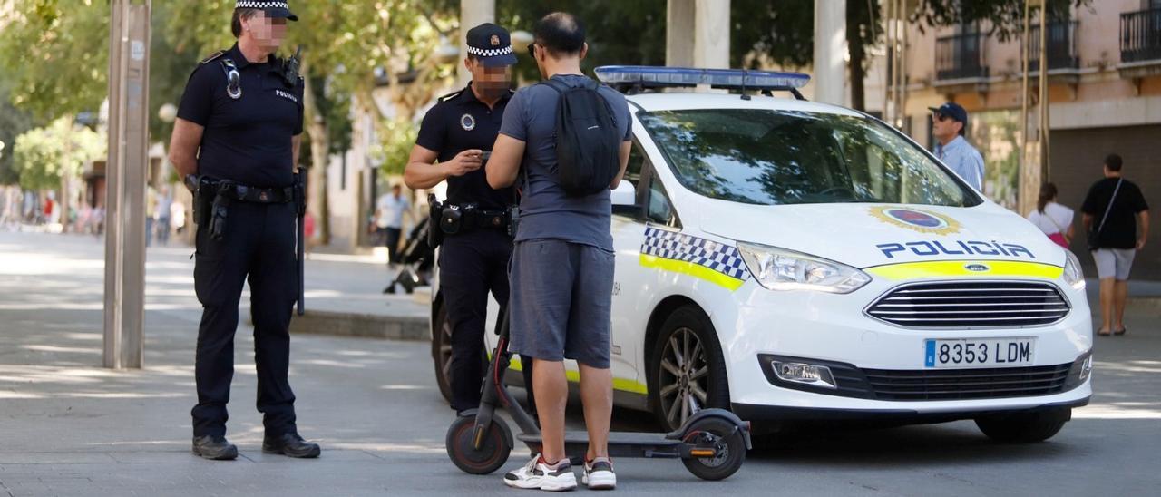 Un conductor de patinete, junto agentes de la Policía Local.