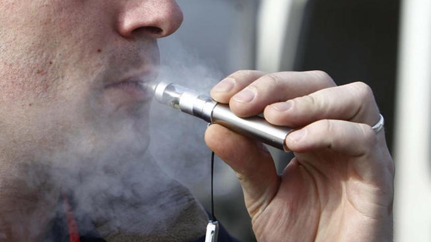 Un joven vapeando con un cigarrillo electrónico.