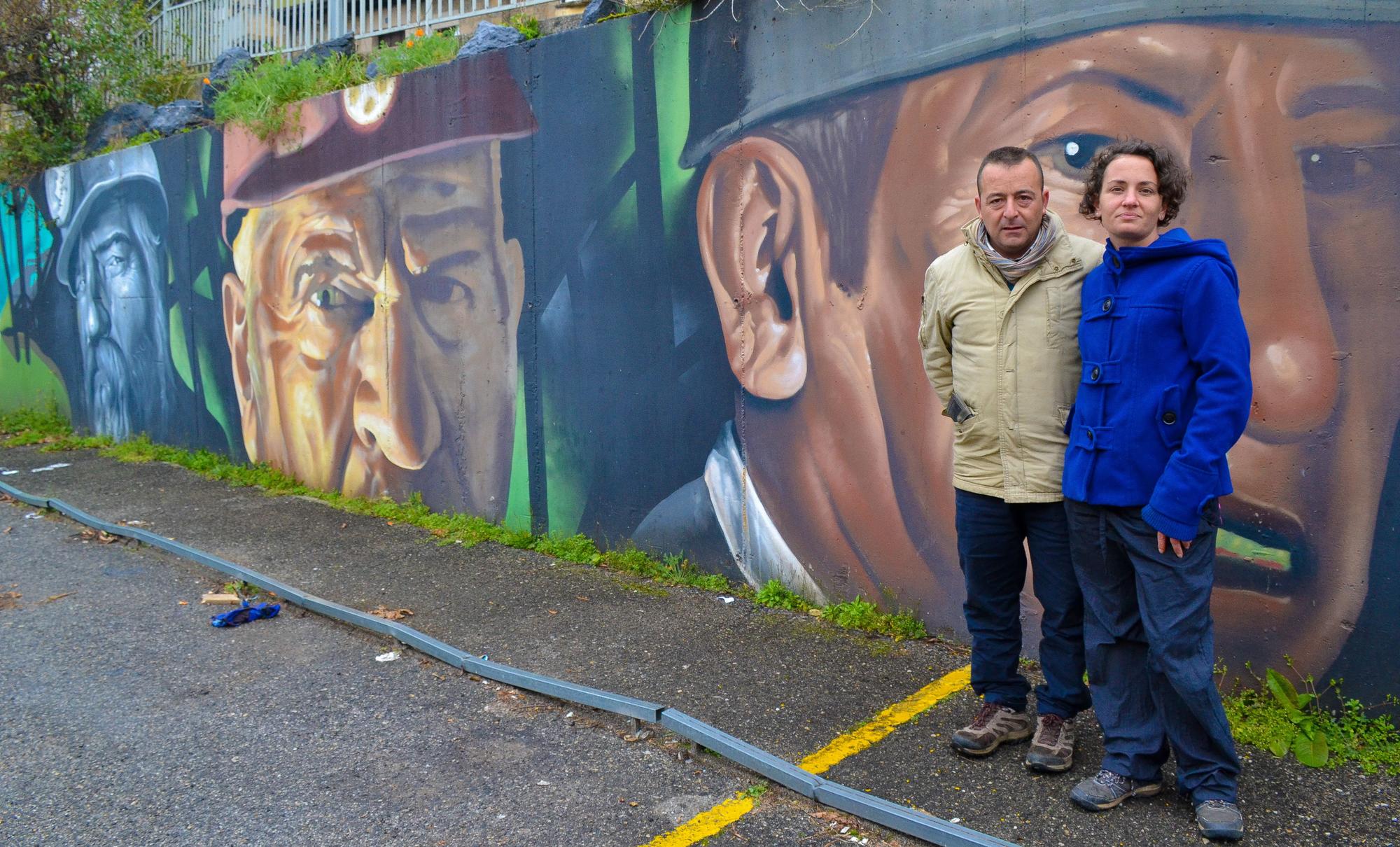 Detalle de la pareja ante uno de los grandes murales dedicados a los mineros en San Julián de Bimenes.