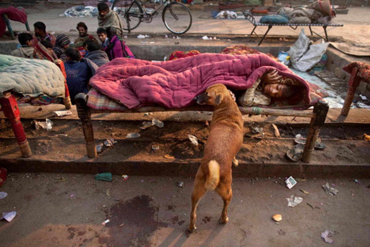 Un noi sense sostre descansa embolicat en un cobrellit en un llit de lloguer, a prop de la mesquita de Jama, a Nova Delhi (Índia).