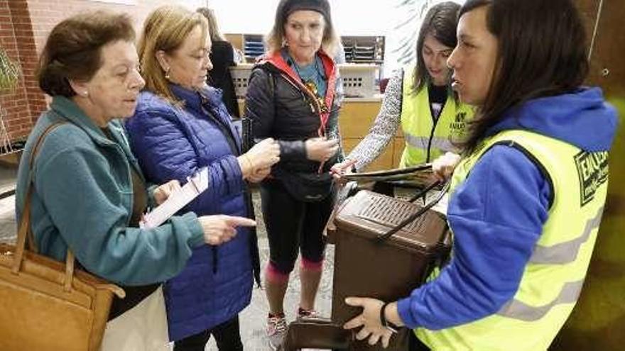 Vecinos de La Arena recogen cubos para el reciclaje en un punto informativo de Emulsa.