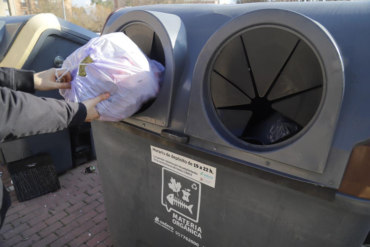 Una persona introduce una bolsa de basura en un contenedor de Sadeco.