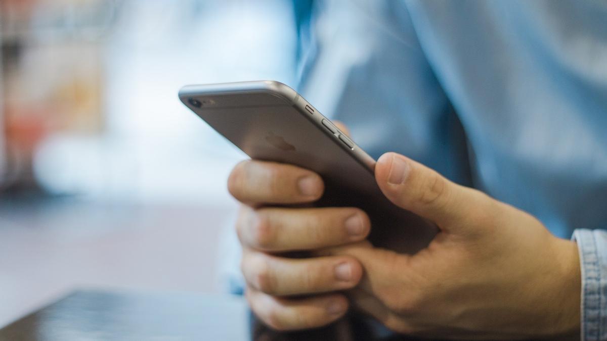 Un hombre consulta un teléfono iPhone.