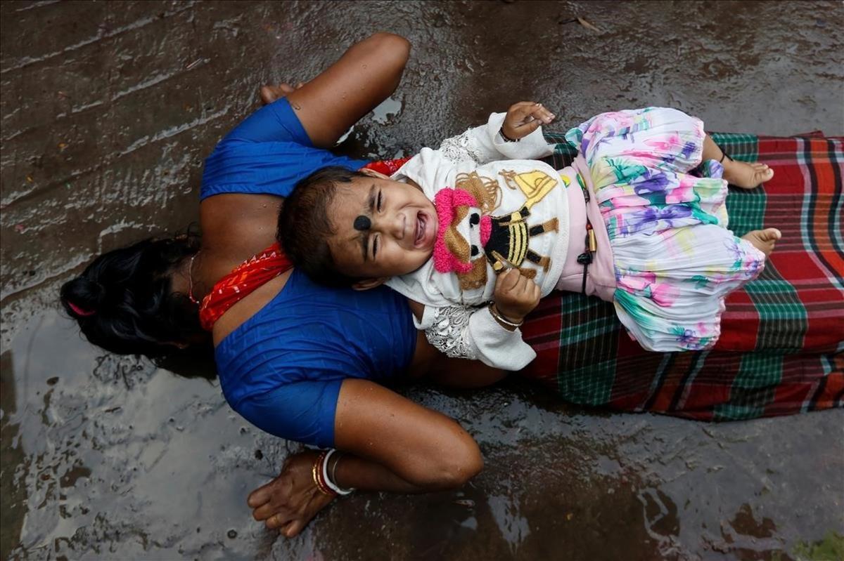 Un bebé en la espalda de una mujer mientras realiza un ritual adorando a Sheetala Mata, la diosa hindú de la viruela durante la Sheetala Puja, en la que los devotos rezan por el mejoramiento de su familia y la sociedad.