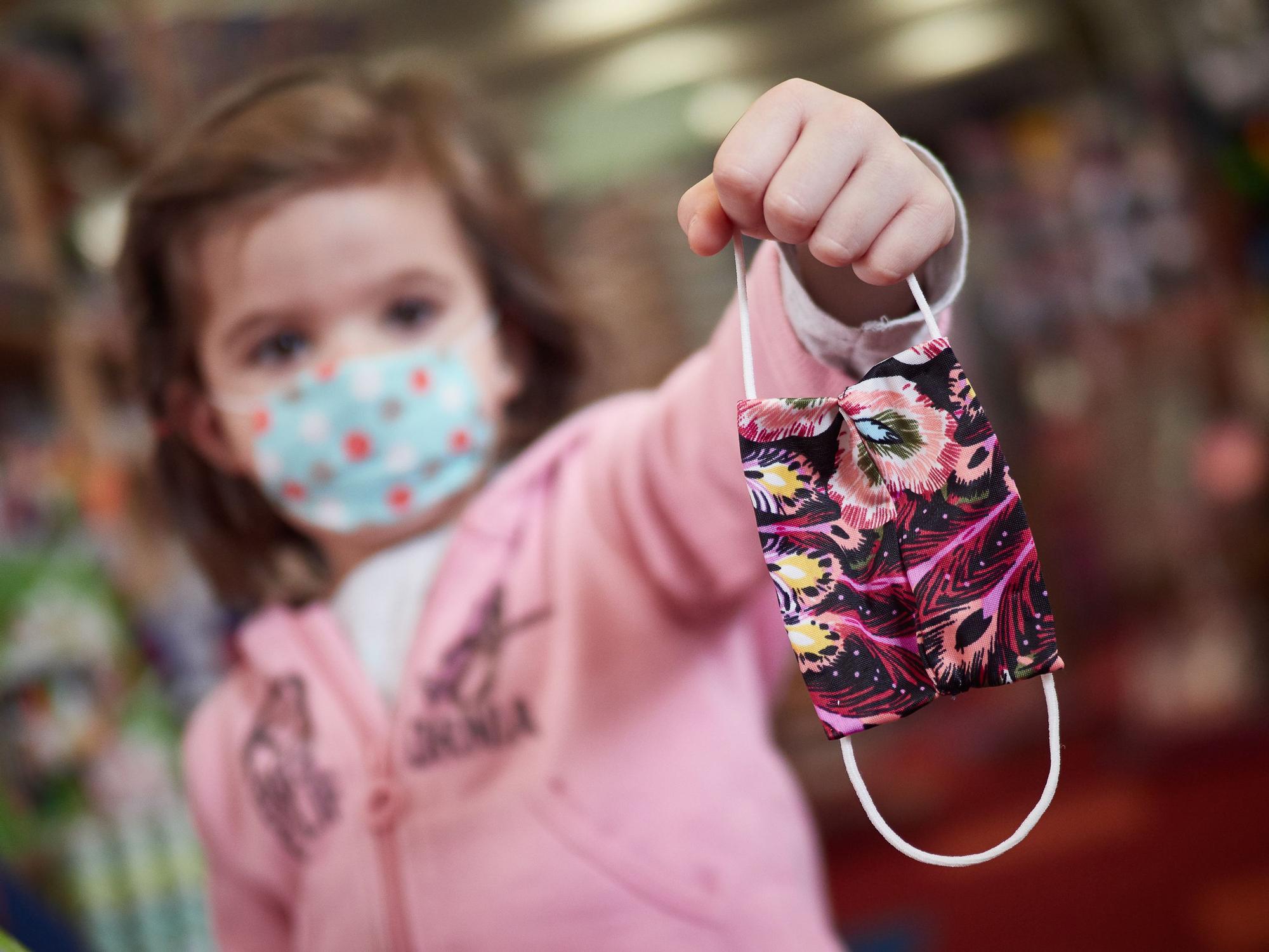 Una niña sujeta una mascarilla infantil