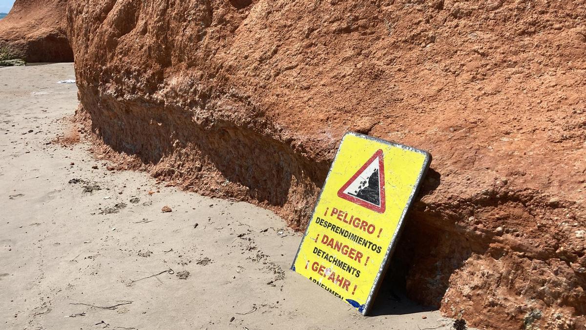 Cartel apoyado junto a los acantilados que advierte de los desprendimientos en Mil Palmeras-Barranco Rubio