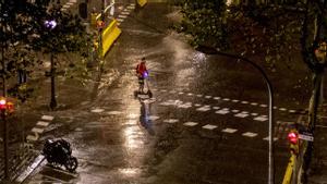 Un patinete cruza una de las calles del Eixample bajo la ligera lluvia de primera hora de la mañana