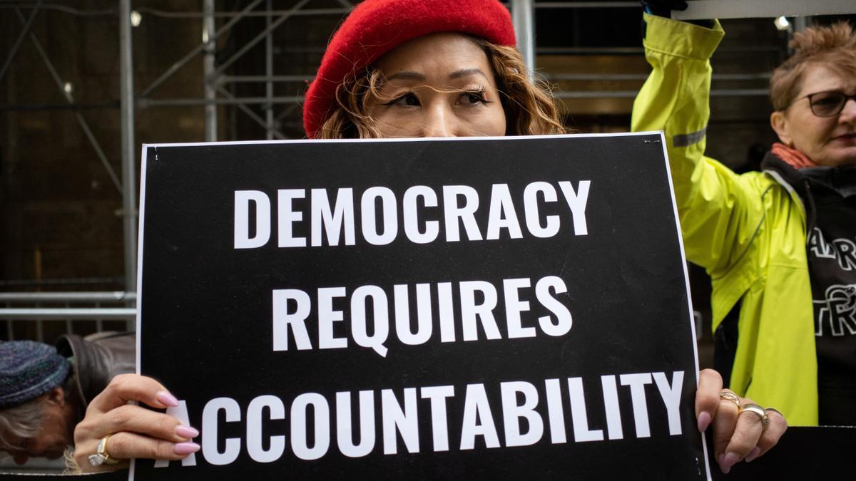 An anti-Trump protestor holds a placard outside the District Attorney's office, in New York City