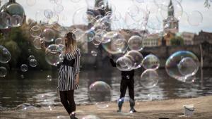 Una chica se hace un selfi rodeada de las burbujas que hace flotar en el aire un artista callejero a orillas del río Moldava, este viernes, en Praga, República Checa.