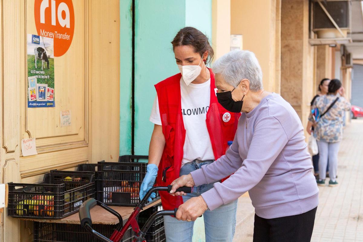 Una mujer con movilidad reducida, acompañada por una voluntaria.