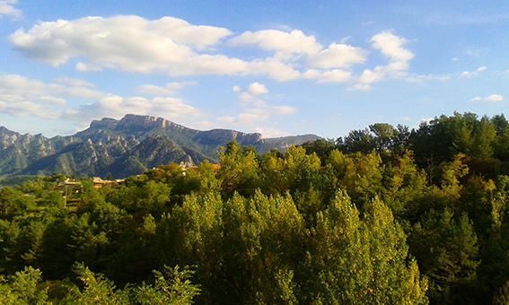 Paisatge. Atractiu paisatge de verdor natural i, al fons, podem veure les muntanyes cobertes per petits nuvolets amb un dia assolellat.