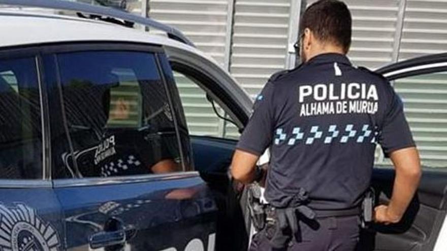 Un agente de Alhama de Murcia, junto al vehículo policial.