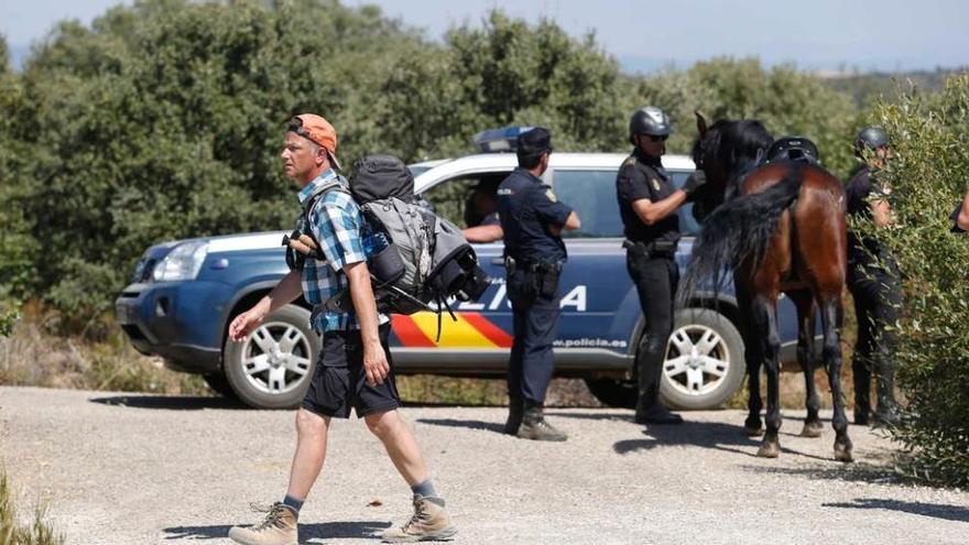 El gran despliegue policial continúa. Un peregrino pasa por delante de varios agentes en Castrillo de los Polvazares.