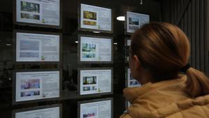 Una mujer mira anuncios de una agencia inmobiliaria en Barcelona