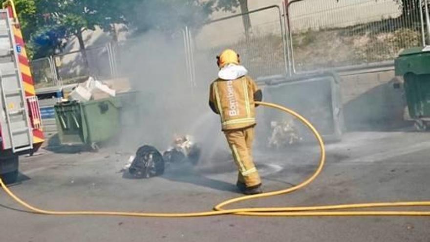 Un bombero apagando el fuego en el contenedor quemado ayer en Petrer.