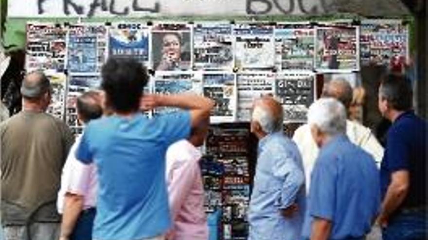 Vianants a Atenes mirant les portades de premsa en un quiosc