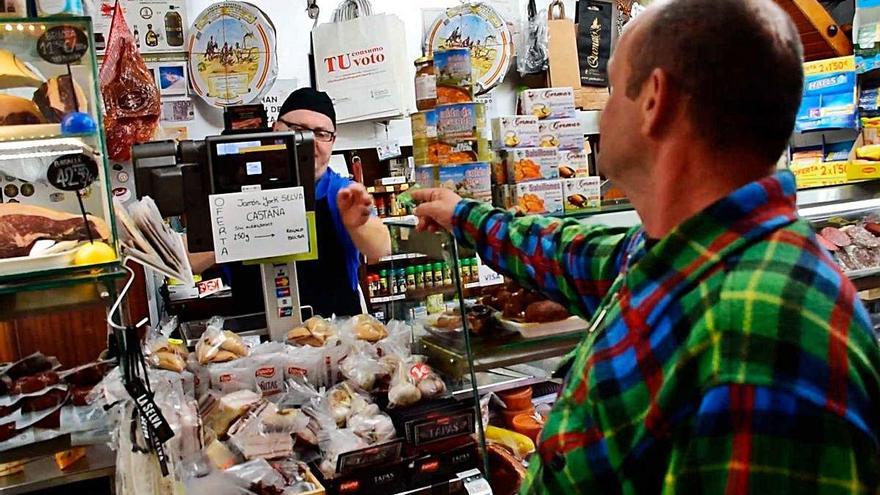 Un cliente paga con una tarjeta prepago de Caixa Popular en un comercio.