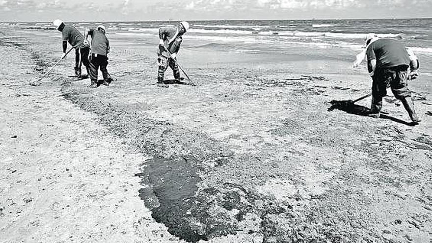 Operarios limpian los restos del vertido en la isla de Elmer.