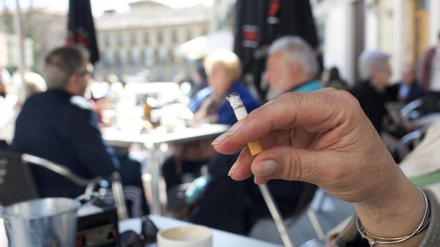 Una clienta fuma un cigarrillo en una terraza de Avilés. | Miki López