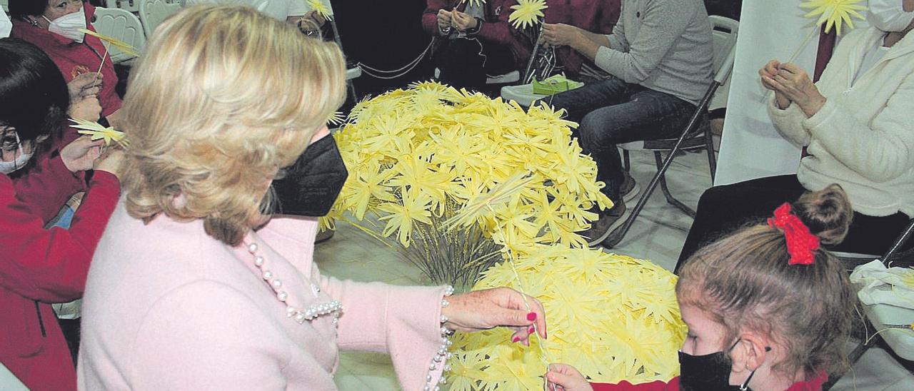 María Dolores Vera con su nieta Lola Navarro haciendo  flores junto a un grupo de blancos.