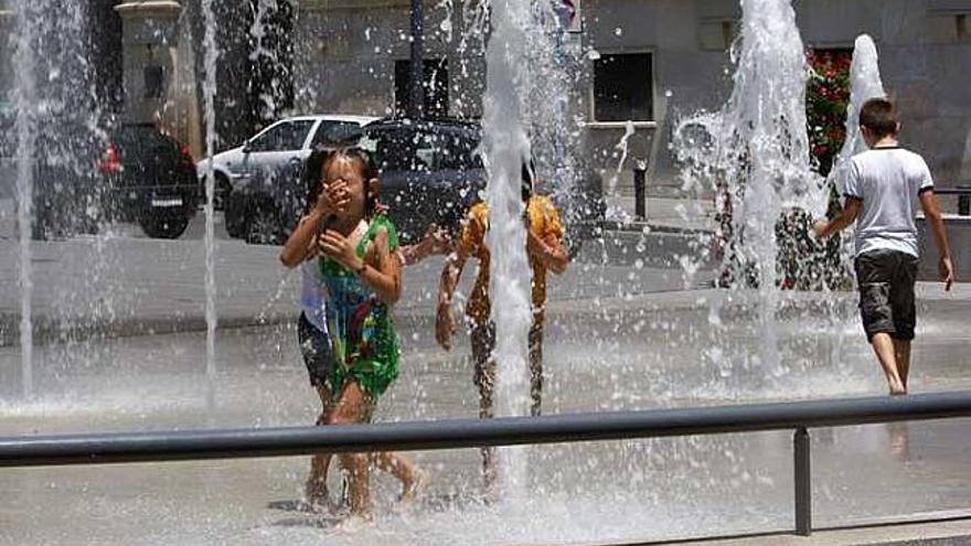 Unos niños se refrescan en la fuente de la Montañeta.