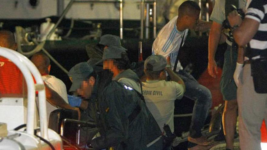 Agentes de la Guardia Civil ayudan a desembarcar a uno de los inmigrantes que llegaron anoche al Puerto de Alicante