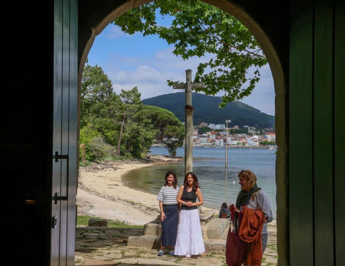 La puerta de la capilla y el
«cruceiro» de Cortegada, con
Carril, al fondo. |  Iñaki Abella