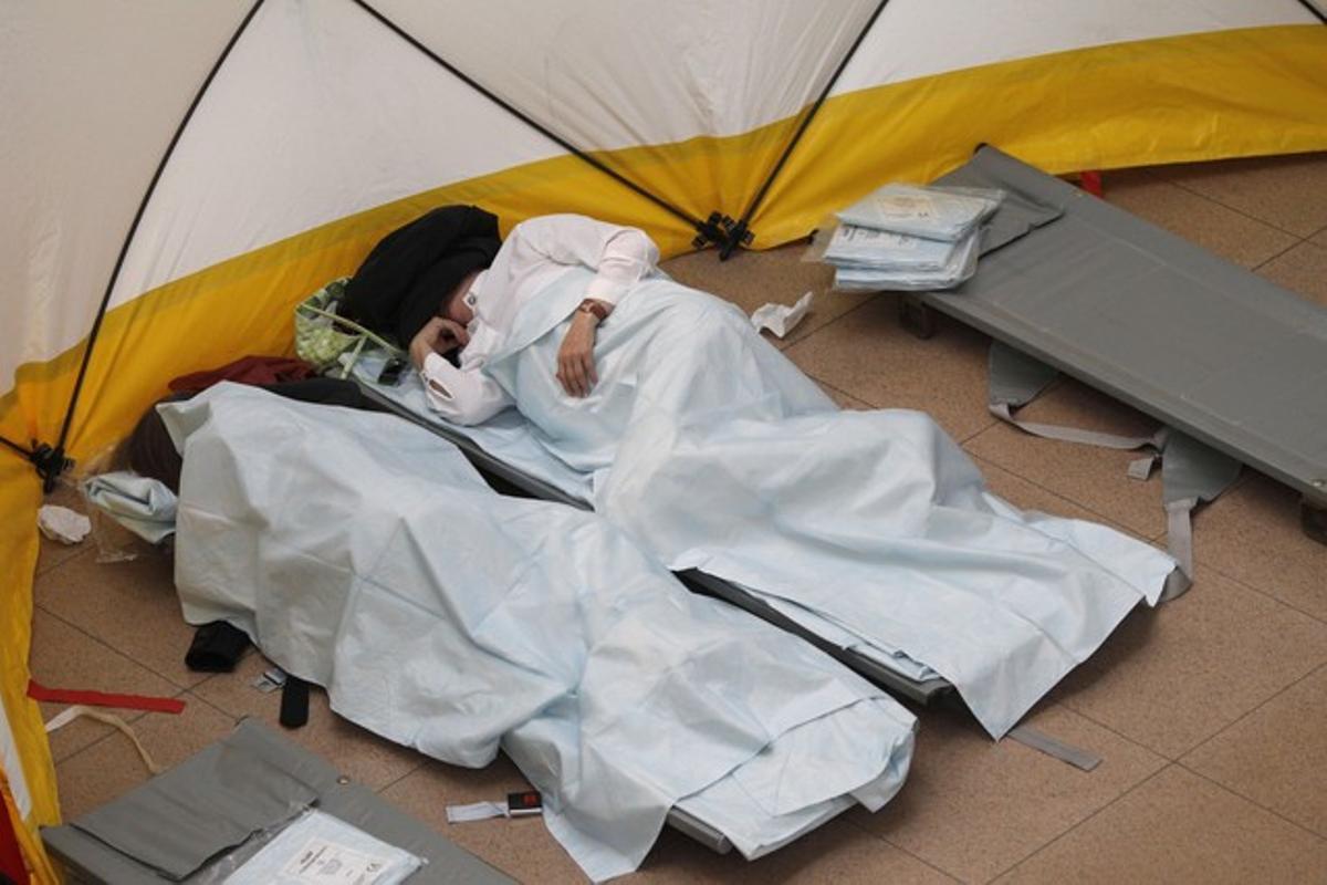 Passengers sleep on camp beds at Hamburg Airport