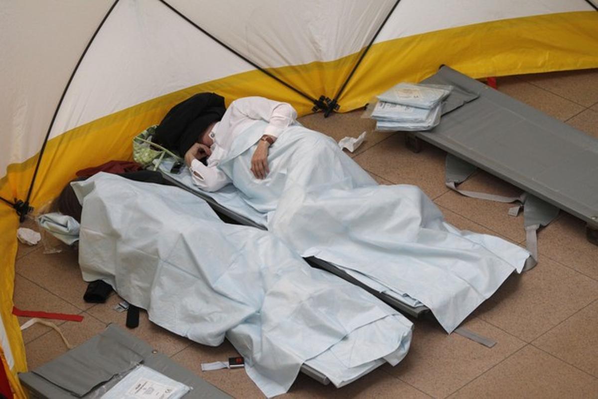 Descanso en esterillas. Dos pasajeros de un avión cancelado duermen en tiendas de campaña en el aeropuerto de Hamburgo (Alemania).