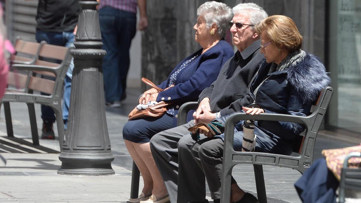 Varios jubilados descansan en un banco.