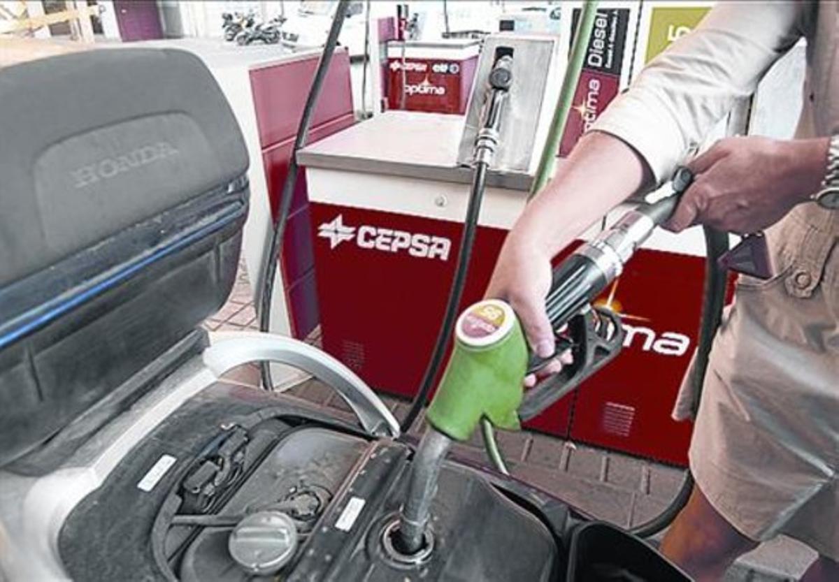 Repostant 8Una client omple el dipòsit de la moto. Repostant 8Una client omple el dipòsit de la moto.