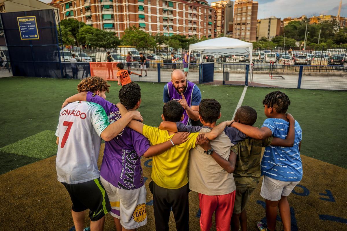 El educador Adrià Cabanillas, junto a un grupo de niños que participan en el proyecto de casals veraniegos para los niños de la calle en La Florida (l'Hospitalet).