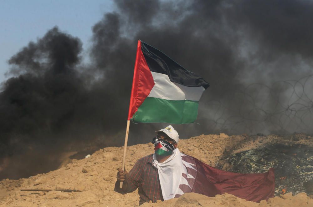 Un manifestante agita una bandera palestina durante enfrentamientos con las tropas israelíes cerca de la frontera entre Israel y la Franja de Gaza central