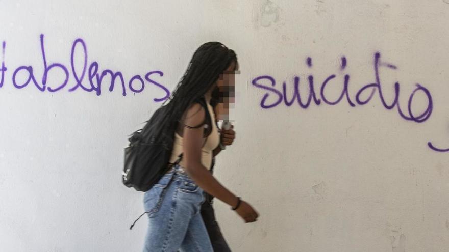 Dos jóvenes pasan ante una pintada sobre el suicidio, en una imagen de archivo.
