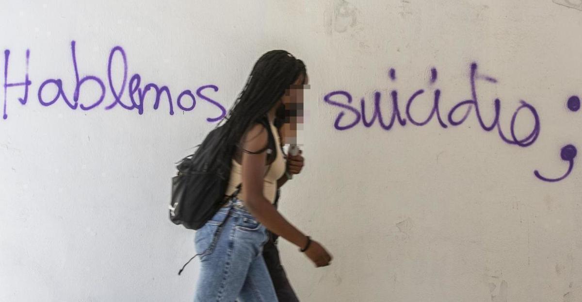 Dos jóvenes pasan ante una pintada sobre el suicidio, en una imagen de archivo.