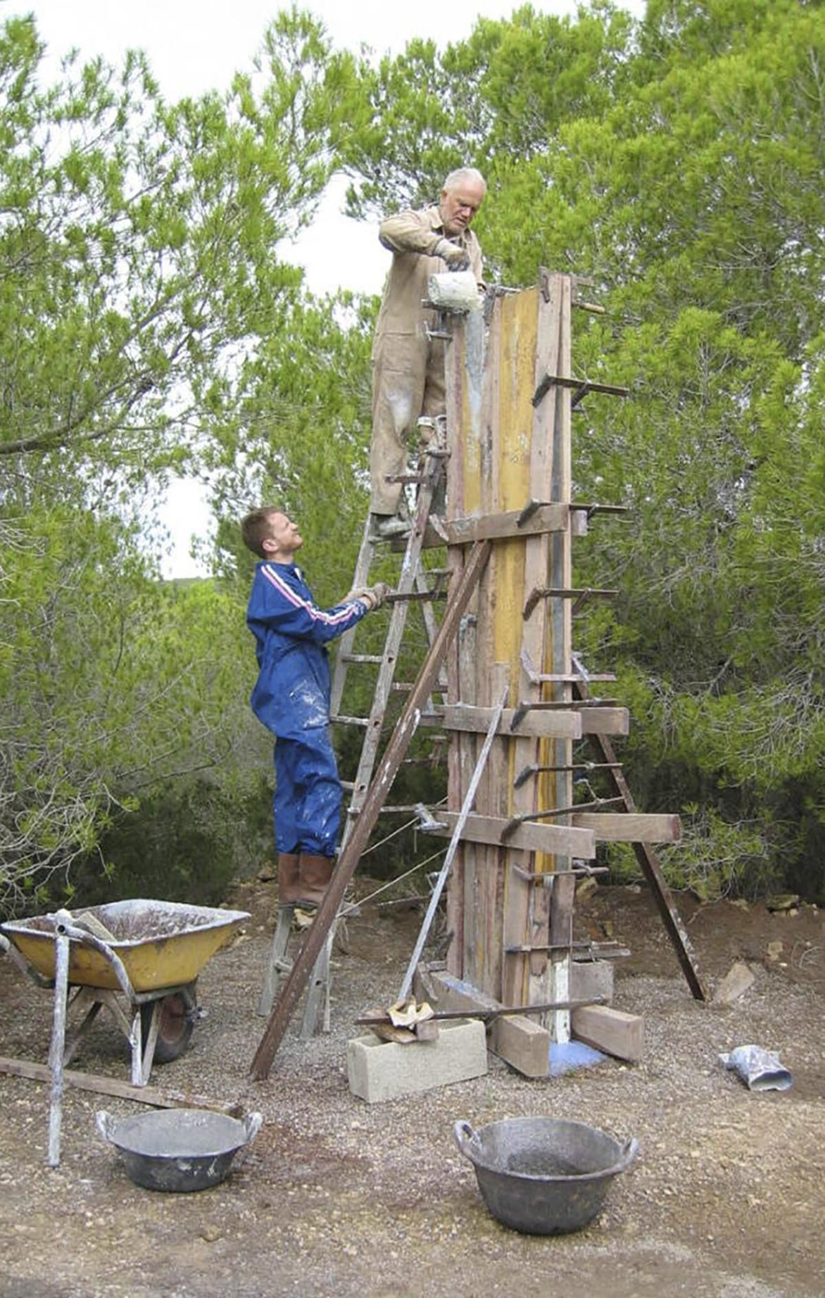 El artista vierte hormigón en un molde con la ayuda de su hijo, Jacopo, en su casa de Sant Carles. / FAMILIA MONTI