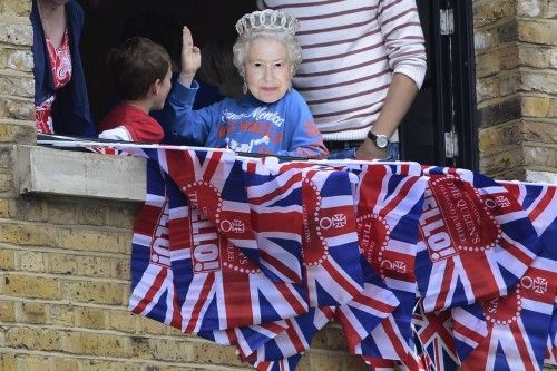 A boy wearing a mask portraying Queen Elizabeth wait for a pageant in celebration of the Queen's Diamond Jubilee in London