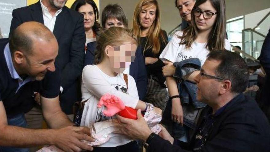 Momento de la entrega de la prótesis de brazo a la pequeña por parte de los dos profesores que la han diseñado